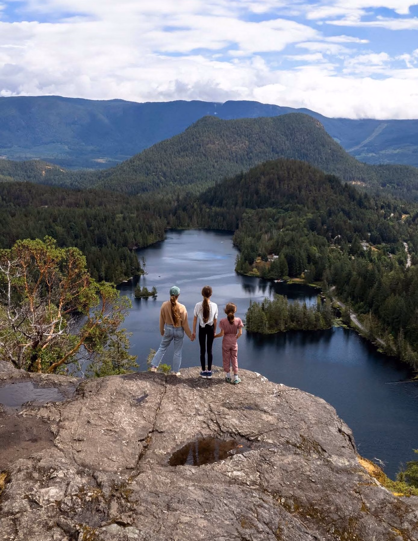three children standing on Pender Hill, Sunshine Coast looking out over a river and mountains.
